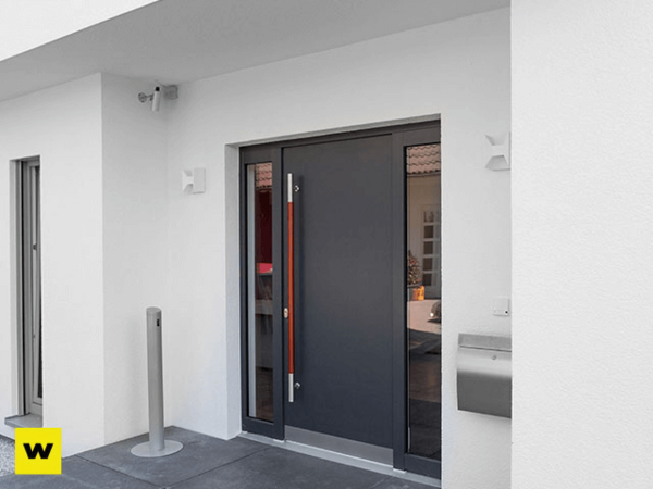 Moderne Haustür aus Aluminium mit Seitenteil an weißer Fassade und Briefkasten.