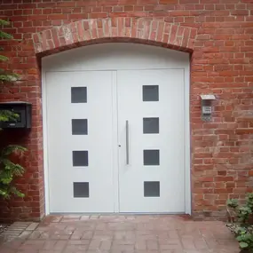Weiße Haustür mit Glasfenstern in roter Backsteinfassade, Eingangstür modern