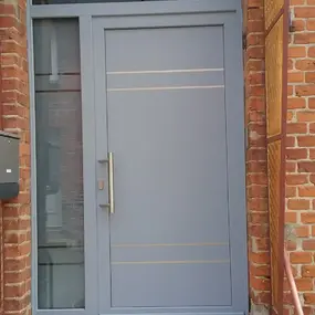 Graue Haustür mit Seitenteil aus Glas in Backstein-Hauseingang