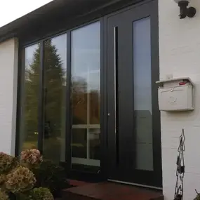 Moderne schwarze Haustür mit Glas, weißer Klinkerfassade und Briefkasten