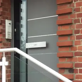Moderne graue Haustür mit Glasstreifen und Briefkasten an Backsteinfassade